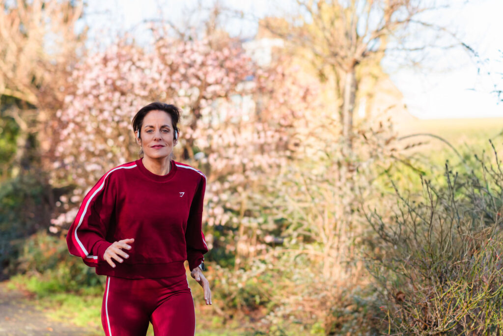 Deb running outdoors, representing the athletic coaching and active lifestyle of the program.